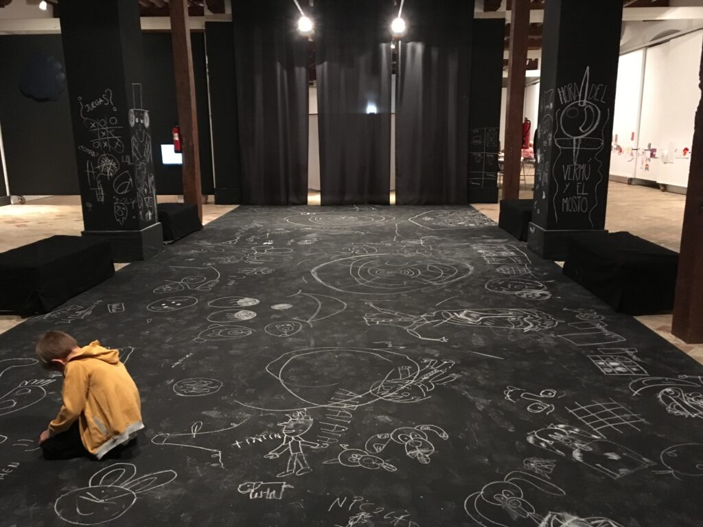 Sala oscura con dibujos de tiza en el suelo de la exposición Es o no es