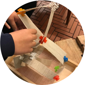 Manos de un niño construyendo con piezas de madera y pinzas