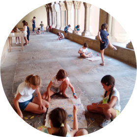 Niños trabajando en el suelo de un claustro de piedra