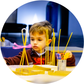 Niño construyendo una estructura con varillas amarillas