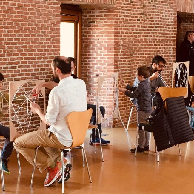 Familias participando en un taller en una sala de muros de ladrillo